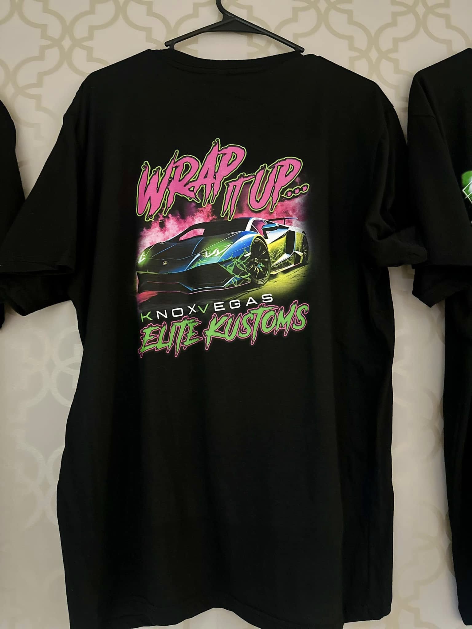 Black t-shirt with colorful graphic design on a white background